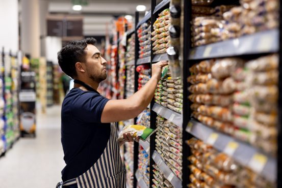 Latin American Retail clerk working at the supermarket restocking the shelves